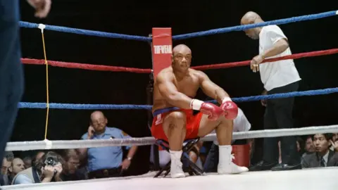 Carlos Schiebeck/AFP via Getty Images Foreman sat inside the ring