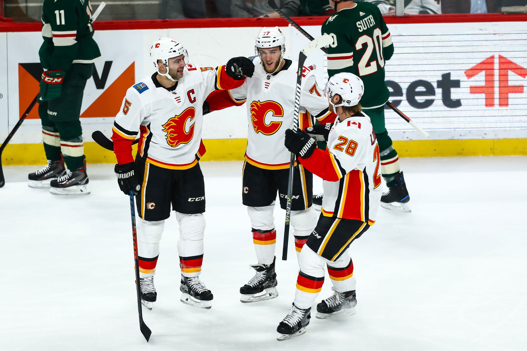 Dec 15, 2018; Saint Paul, MN, USA; (L-R) Calgary Flames defenseman Mark Giordano (5) celebrates with center Mark Jankowski (77) and center Elias Lindholm (28) after scoring a goal against the Minnesota Wild in the first period at Xcel Energy Center. (David Berding-Imagn Images)