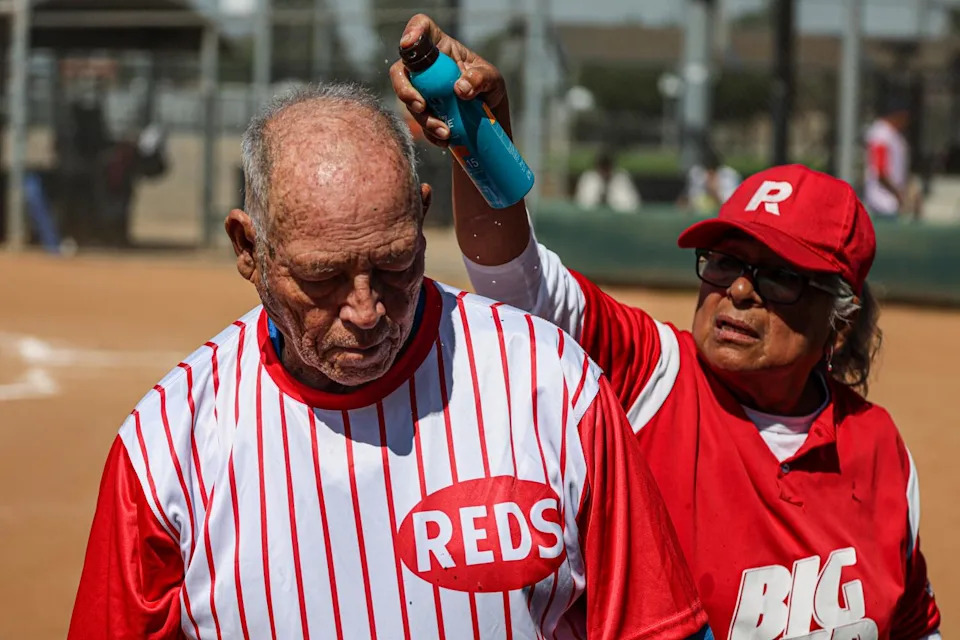 A man in a red uniform sprays the head of a player.