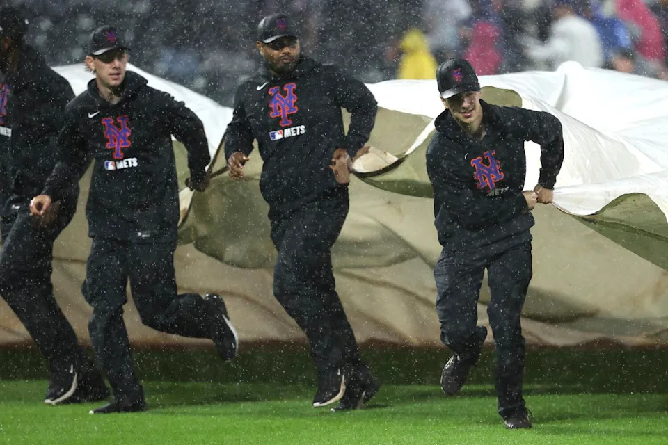 Grounds crew members cover the field during a rain delay at Citi Field on Friday night.