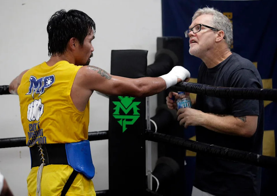 Boxing champion Manny Pacquiao works out with trainer Freddie Roach in front of media member at Wild Card Boxing Club.
