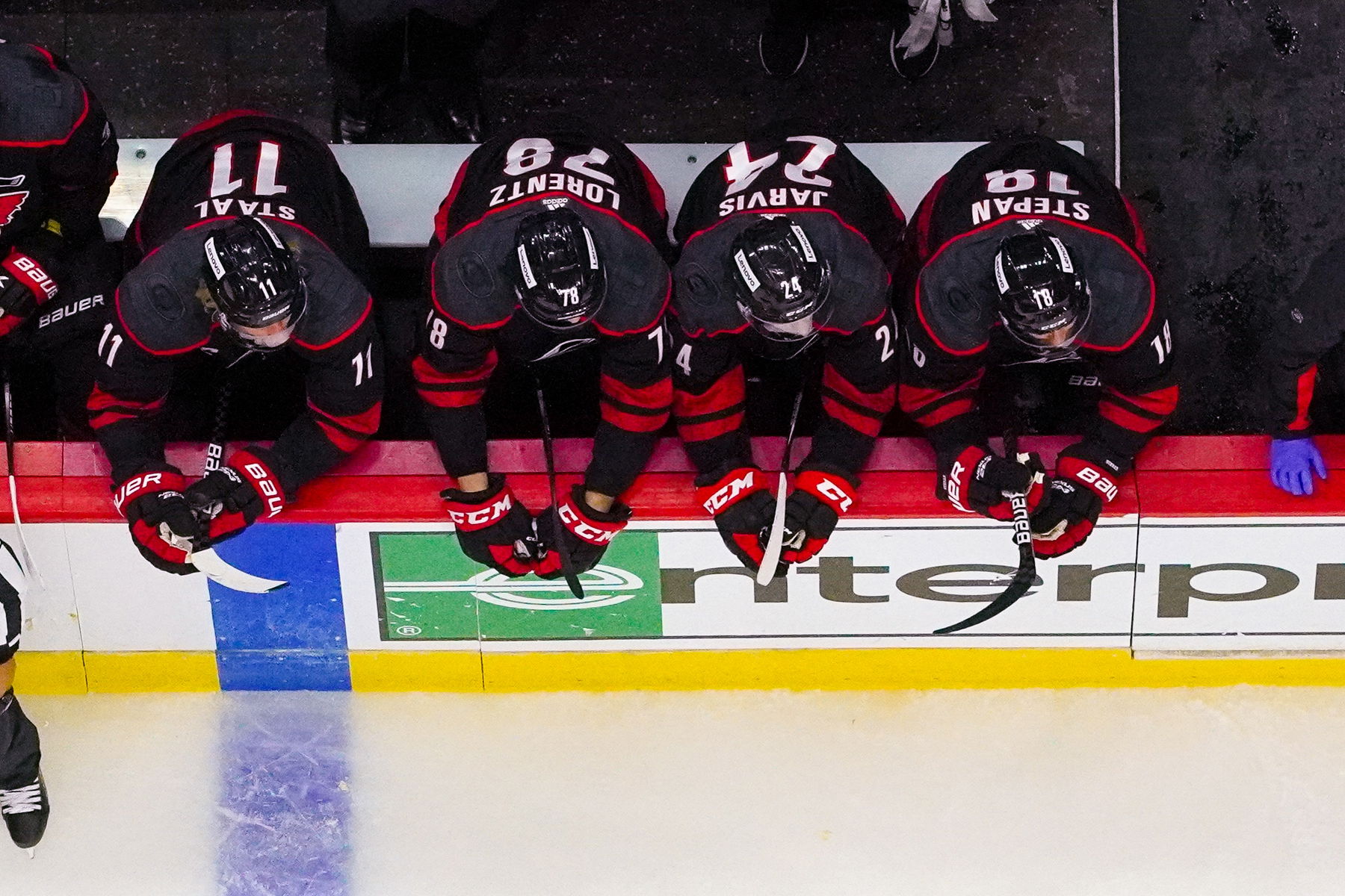 Oct 31, 2021; Raleigh, North Carolina, USA; Carolina Hurricanes center Seth Jarvis (24) sits along side center Derek Stepan (18) center Steven Lorentz (78) and center Jordan Staal (11) in his 1st NHL game against the Arizona Coyotes at PNC Arena. (James Guillory-Imagn Images)