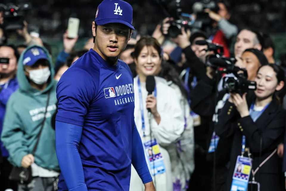 Shohei Ohtani walks past a throng of journalists.