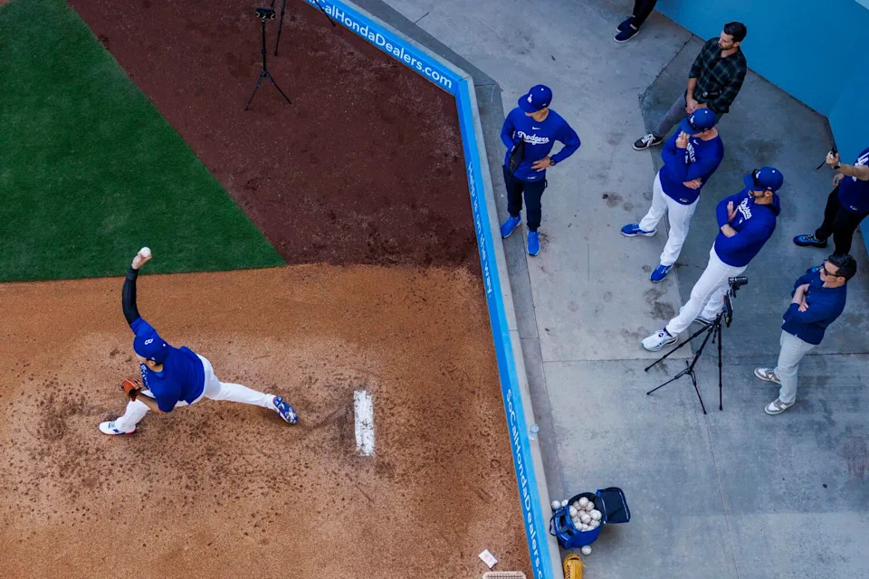 Dodgers coaches keep a watchful eye as Shohei Ohtani (17) pitches in the bullpen before the game against the New York Mets.