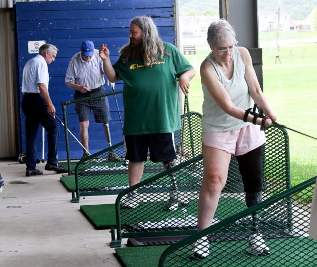 Beth Kase of Mohnton, a quadruple amputee, swings a golf club with help from a special brace that holds the club firmly. The Reading Hospital Rehabilitation at Wyomissing in partnership with the Eastern Amputee Golf Association held a golf clinic for amputees on Tuesday at Sittler Golf, 497 Mountain Home Road, South Heidelberg Township. (BILL UHRICH/READING EAGLE)