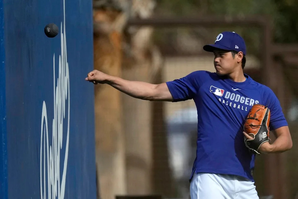 Dodgers' Shohei Ohtani warms up during a baseball spring training workout in Phoenix.