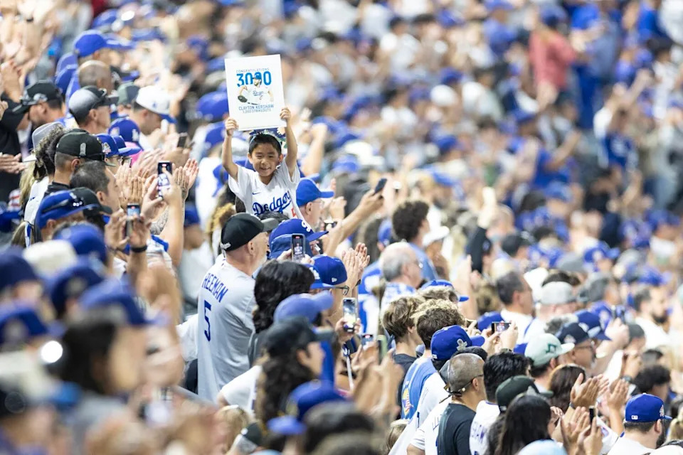 A young Dodgers fan holds up a sign that reads "3,000" to celebrate Clayton Kershaw's strikeout milestone.
