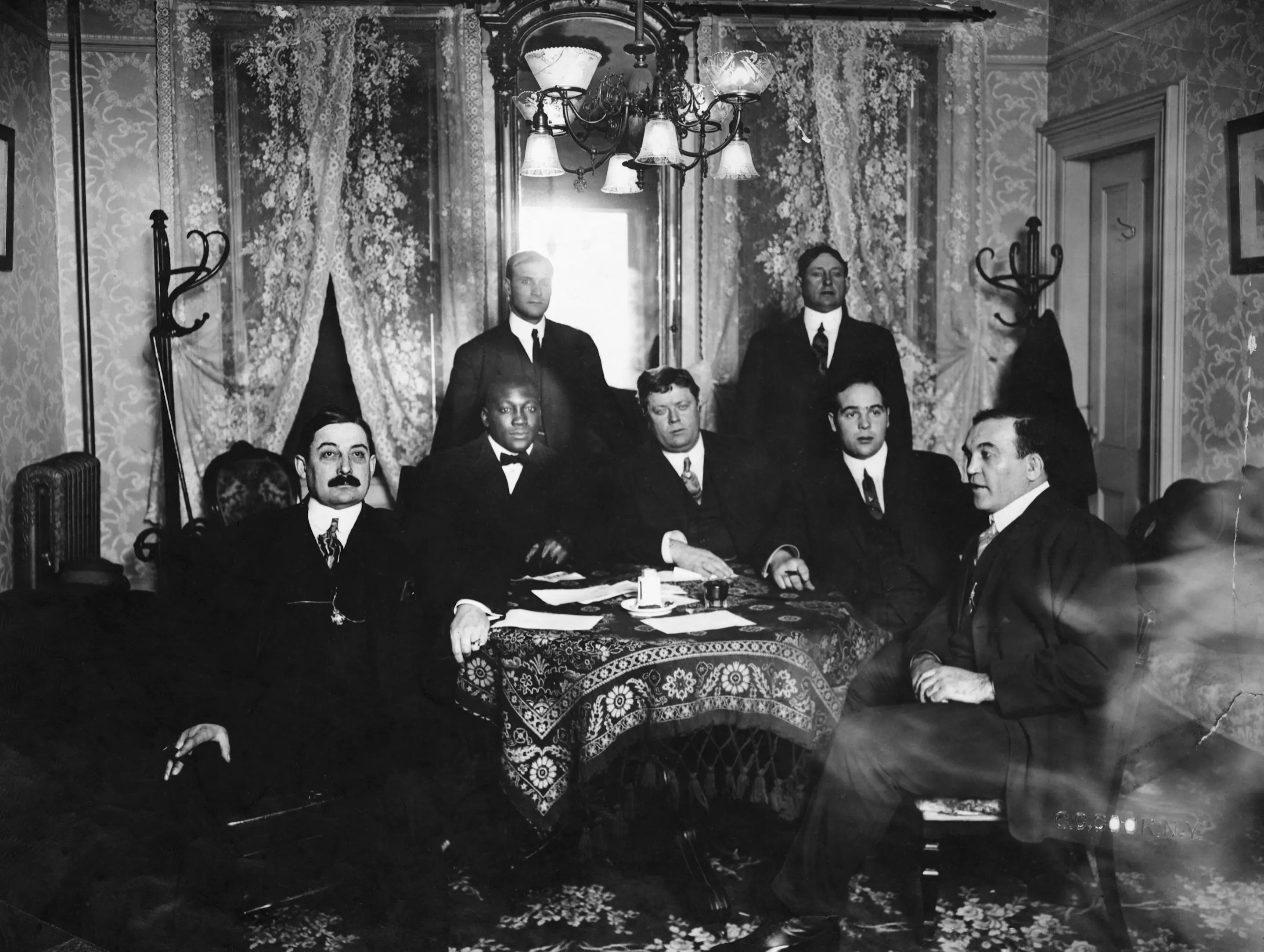 (Original Caption) Manager George Little and Jack Johnson close deal for big fight with various promoters, managers and fighters. Jim Jeffries seated at right. Photograph.