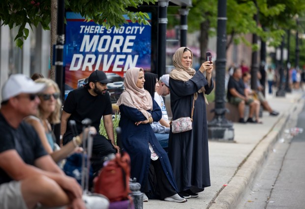 People along Michigan Avenue catch a glimpse of the NASCAR Chicago Street Race through the barriers on July 6, 2025, in Grant Park. (Brian Cassella/Chicago Tribune)