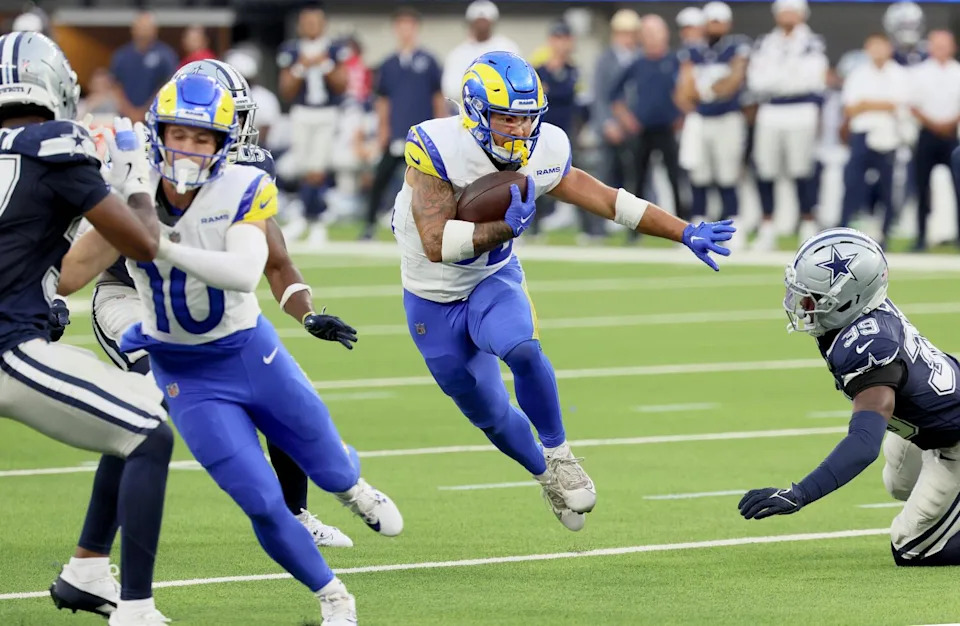 Rams running back Cody Schrader carries the all past Cowboys defensive back Mike Smith during a preseason game.