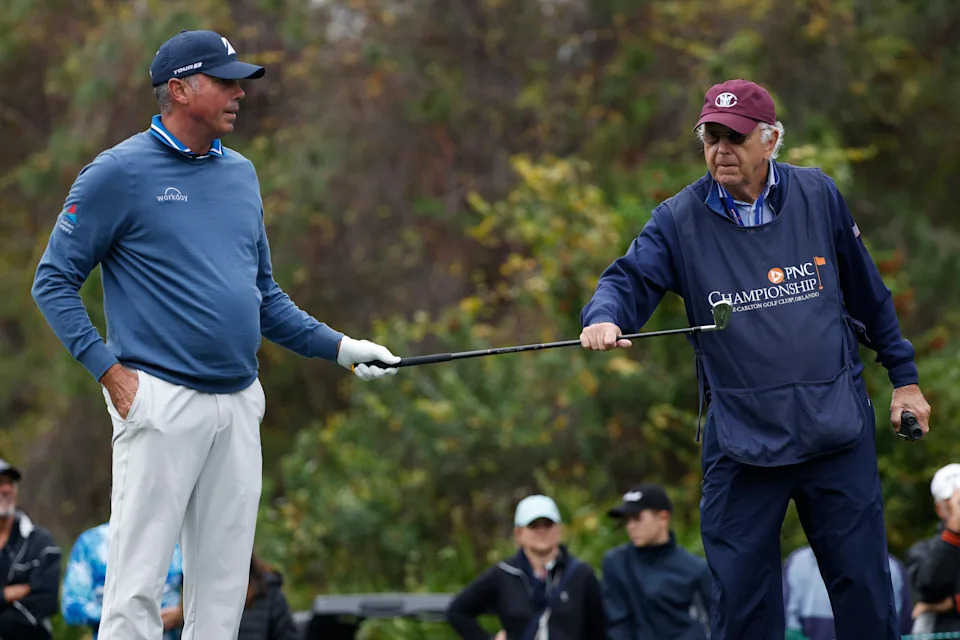 Matt Kuchar hands a club to his caddie and father, Peter, on the fourth hole during the final round of the 2023 PNC Championship at The Ritz-Carlton Golf Club.