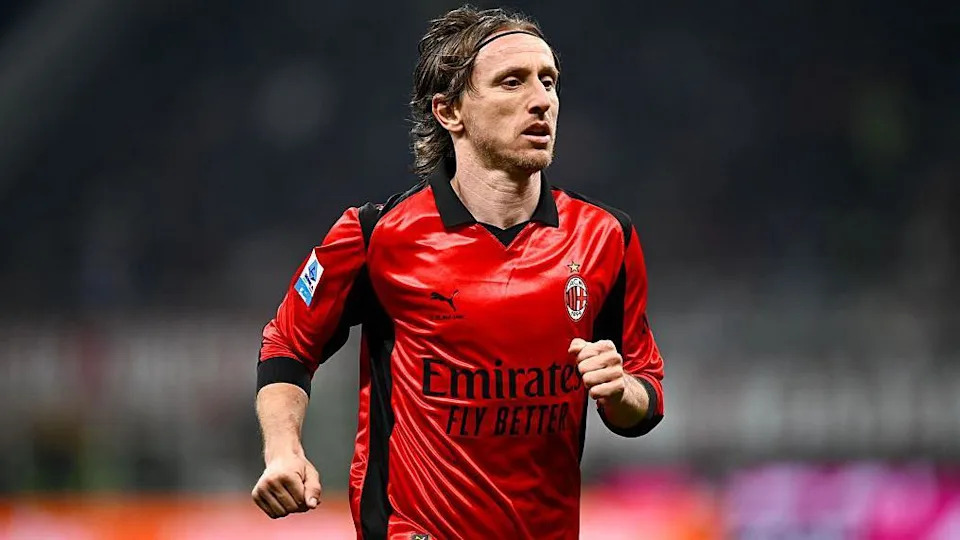 Luka Modric runs in a red AC Milan shirt