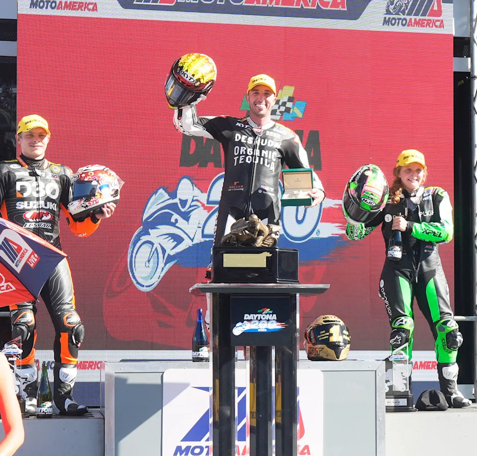 Josh Herrin celebrates another Daytona 200 win on the Victory Lane podium. He's flanked by the other top-3 finishers, Tyler Scott (left) and Kayla Yaakov, the first woman to make the Daytona 200 podium.