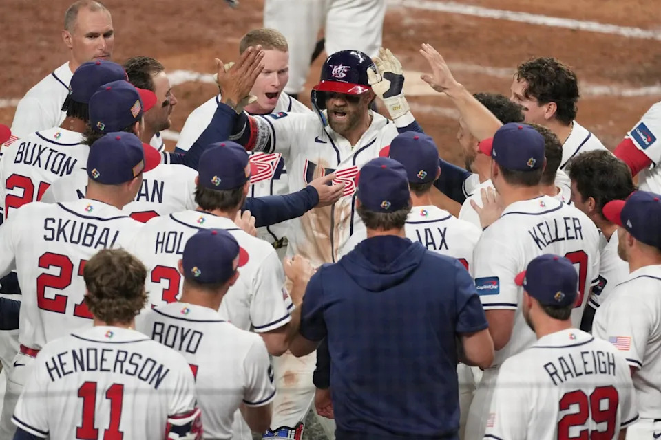 American Bryce Harper celebrates at home plate with teammates after hitting a two-run home run.