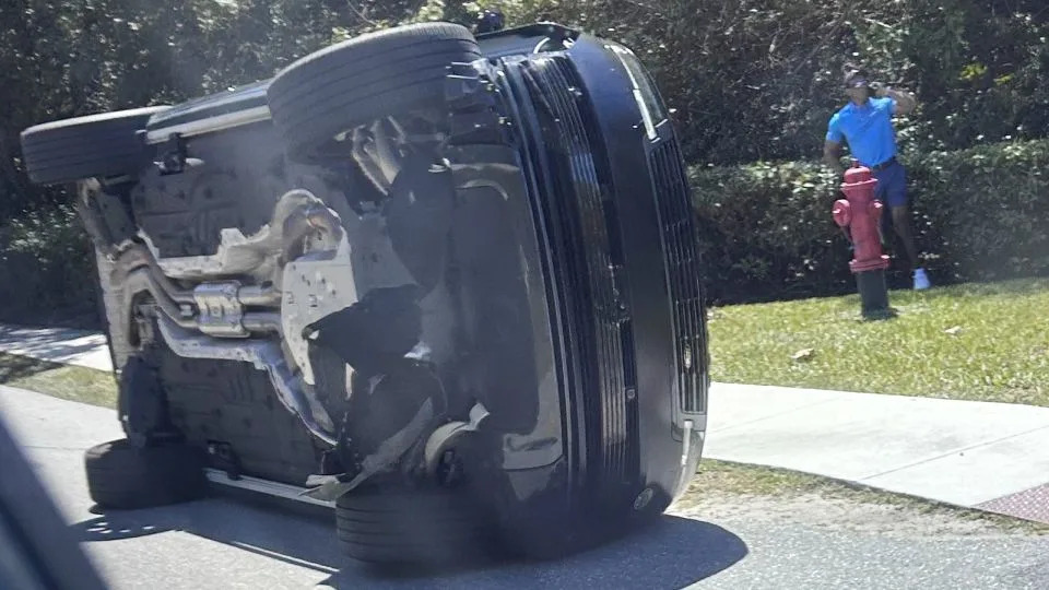 Golfer Tiger Woods stands by his overturned vehicle in Florida on Friday - Jason Oteri/AP