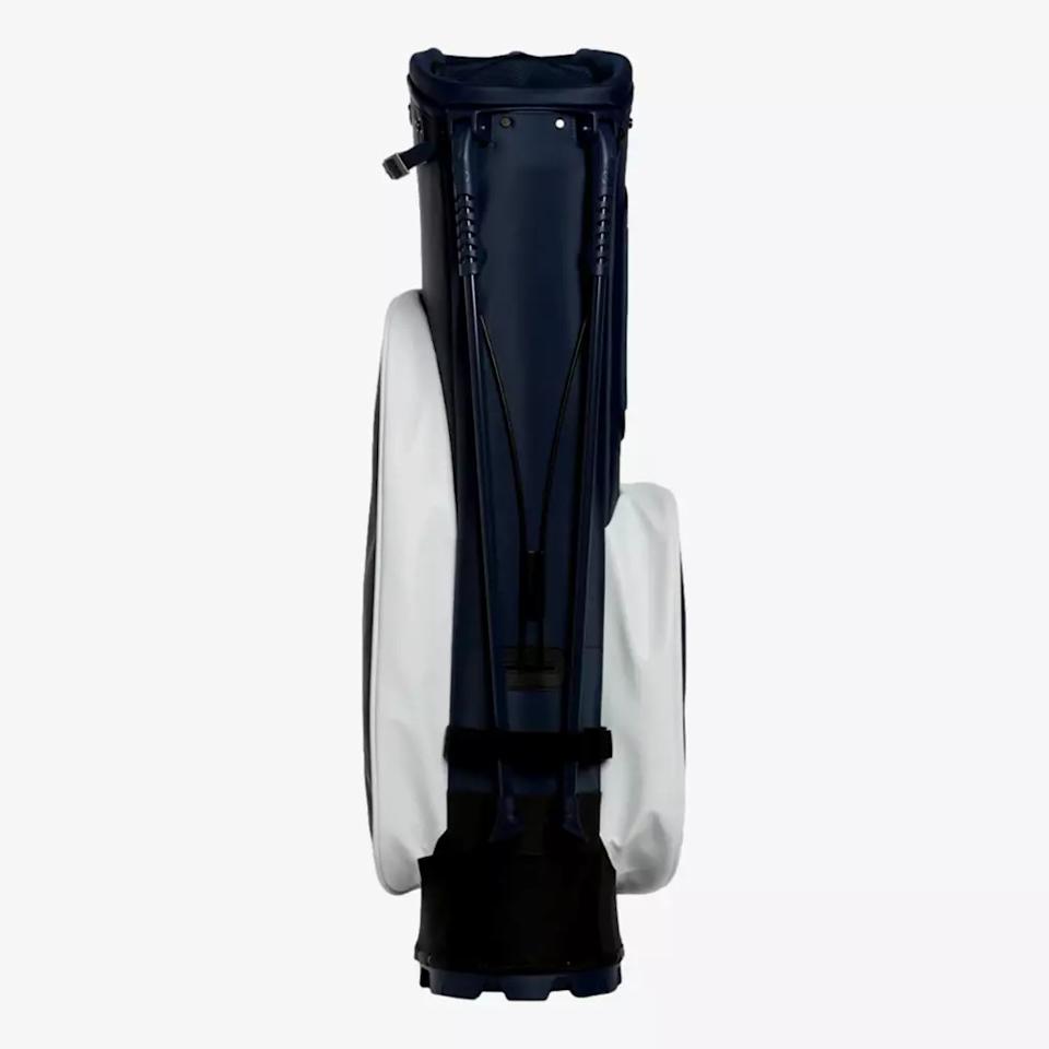 A navy blue golf bag with white side panels, viewed from the front, stands upright against a plain white background. The bag, featuring a handle and black straps, is a stylish choice among the best golf bags 2026 has to offer.