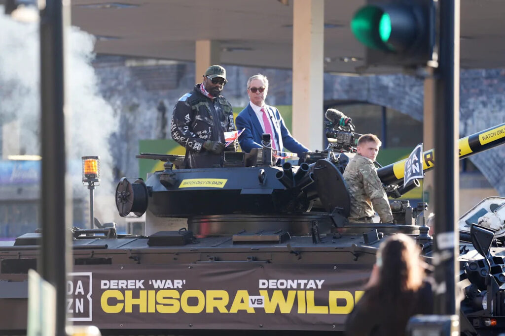 Heavyweight boxer Derek Chisora rides army tank with Nigel Farage to press event