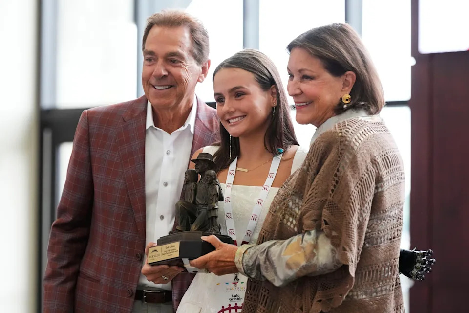Lulu Gribbin, posing between Nick and Terry Saban, received the Greater Than The Game Award at Bryant-Denny Stadium in Tuscaloosa, Alabama in August 2025.