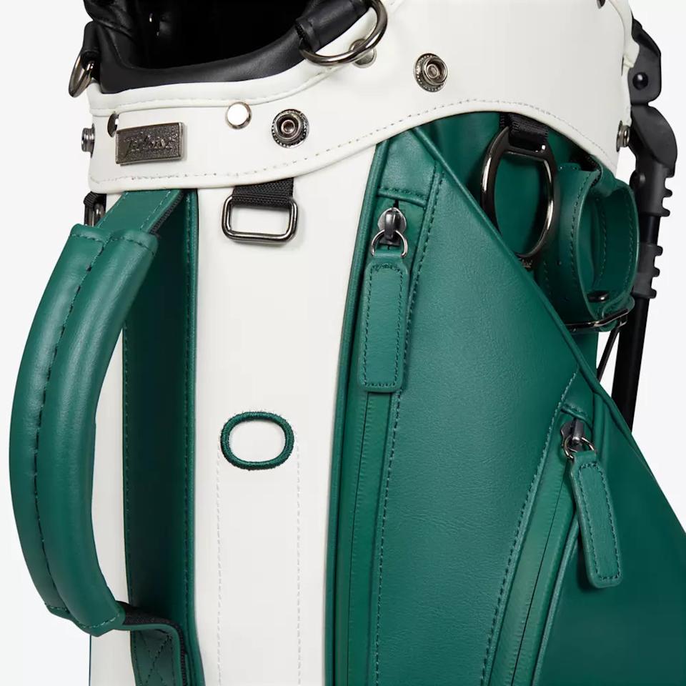 Close-up of a green and white golf bag featuring metal hardware, zippers, and handles, with visible stitching and textured leather-like material—showcasing features you’ll find in the best golf bags 2026.