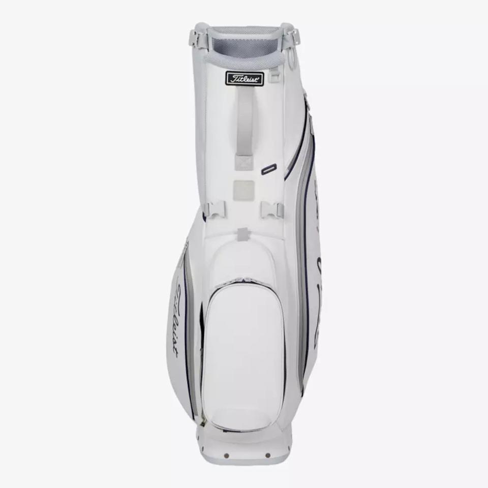 A white Titleist golf bag with multiple zippered compartments and handles, standing upright on a plain light background. The Titleist logo is visible on the side and near the top—an excellent choice among the best golf bags 2026.