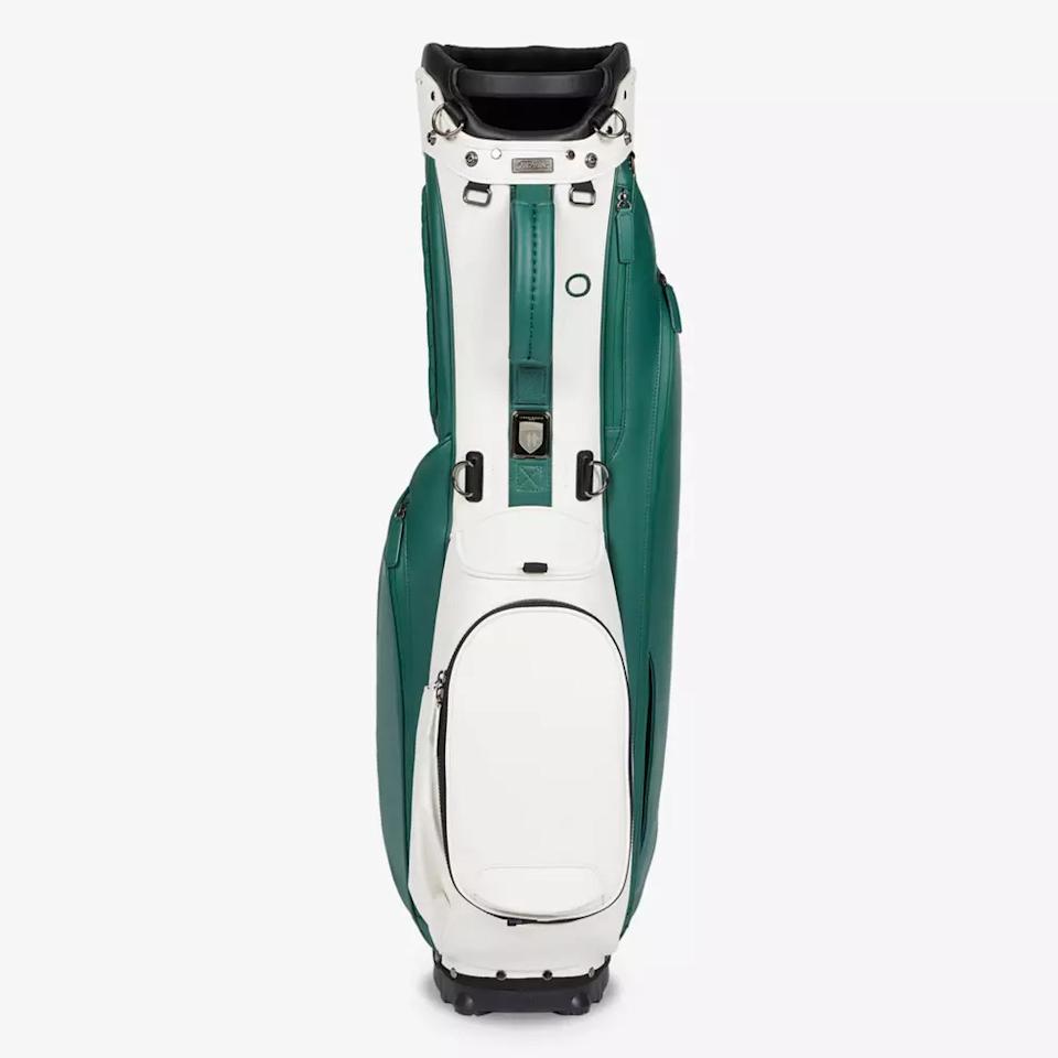 A white and green golf bag standing upright with multiple zippered pockets and a black handle on top—an ideal choice for those seeking the best golf bags 2026 for carrying clubs and accessories.