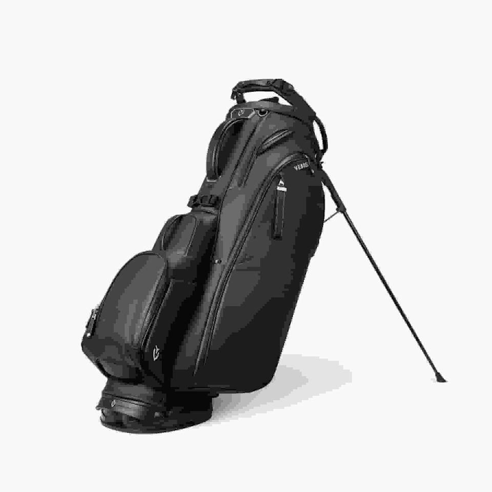 A black golf bag with multiple zippered compartments and a stand, positioned upright on its legs against a white background—an ideal choice for those seeking the best golf bags 2026 has to offer.