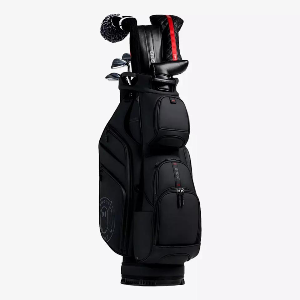 A black golf bag filled with clubs, some with black and red headcovers and a black-and-white pompom headcover. Several zippered pockets and a Callaway logo make this a stylish pick among the best golf bags 2026 has to offer.