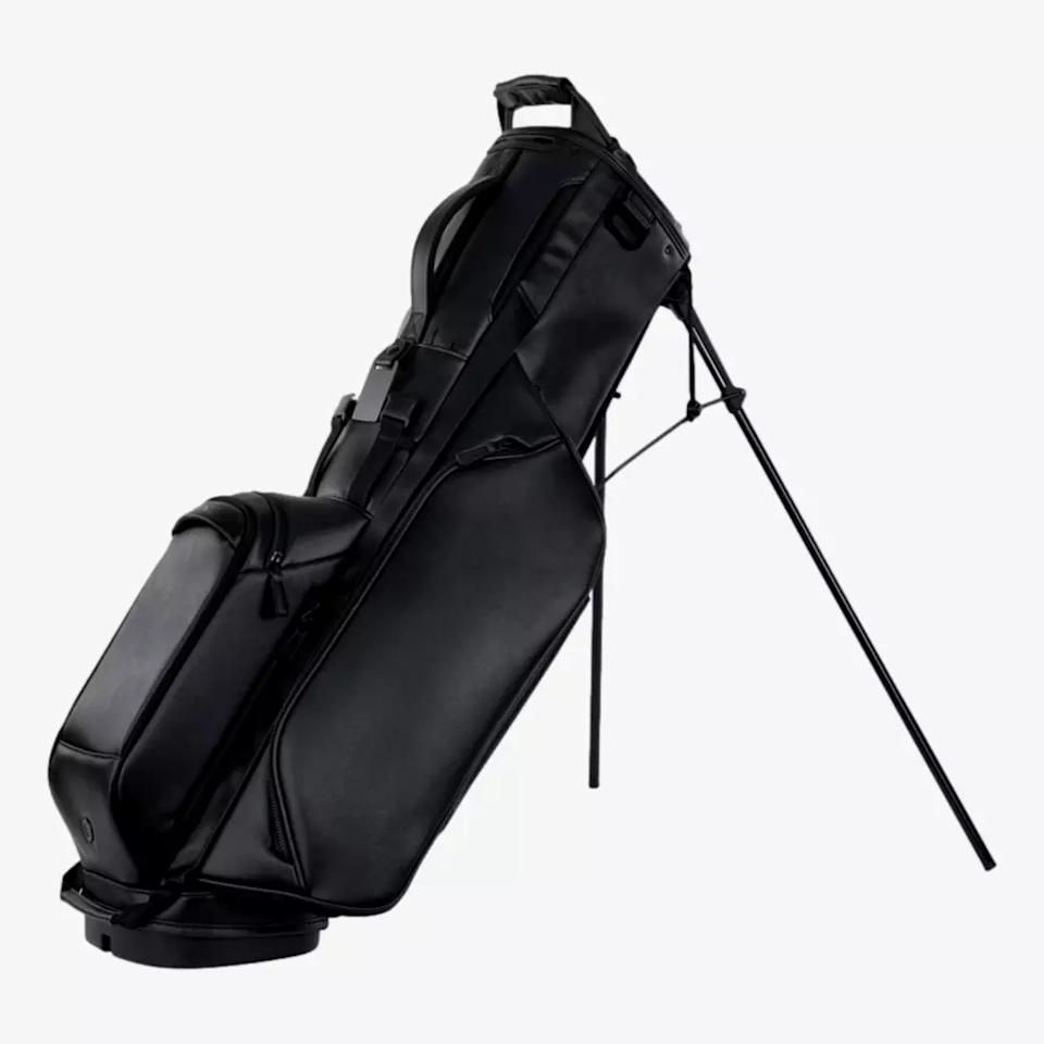 A sleek black golf bag with two extended legs for standing support, multiple zippered compartments, and a padded handle on top—an ideal pick among the best golf bags 2026 has to offer.