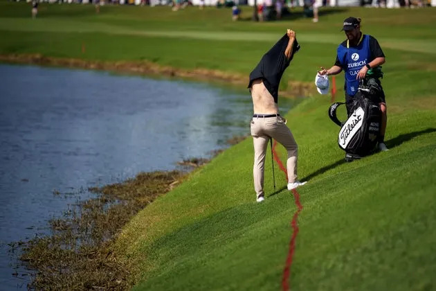 Brennan takes his shirt off before trying to hit his ball out of floating debris on the 18th hole.