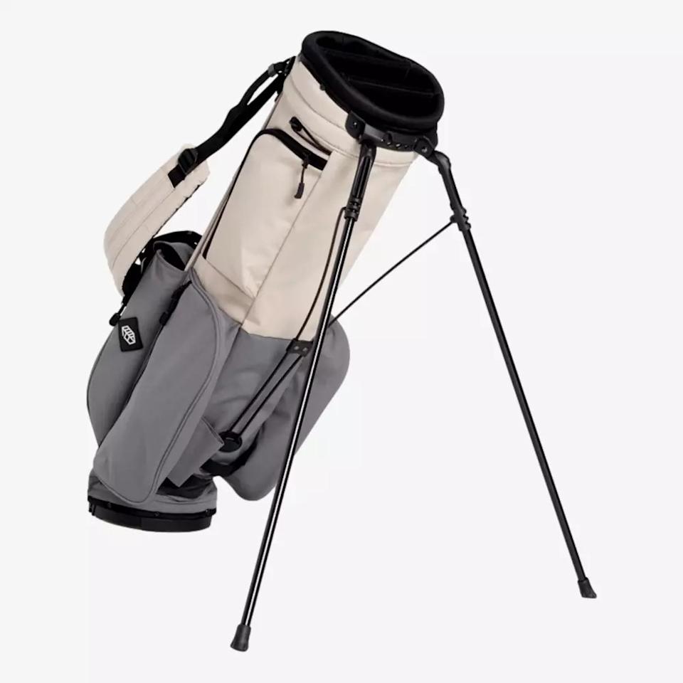 A beige and gray golf stand bag, one of the best golf bags 2026, features multiple pockets and sturdy black legs extended for support, shown against a plain white background.