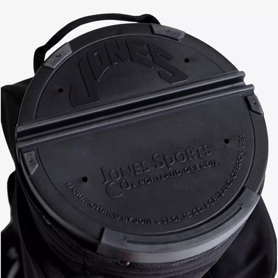 Close-up of a black circular cover with embossed text JONES and Jones Sports Co. Portland, Oregon on a bag, exemplifying the sturdy construction found in the best golf bags 2026, with a convenient top handle.