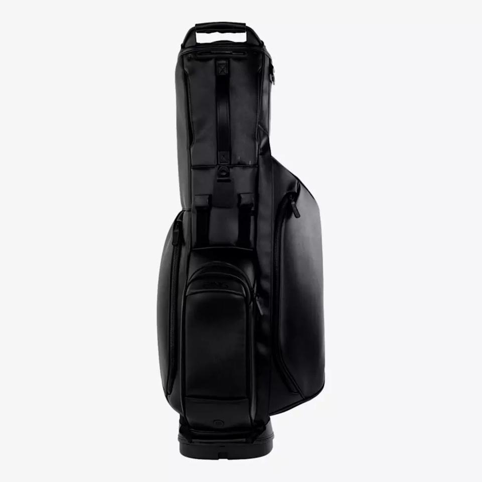 A sleek, black, modern golf bag—one of the best golf bags 2026 has to offer—with multiple zippered compartments and a sturdy handle, standing upright on a plain white background.