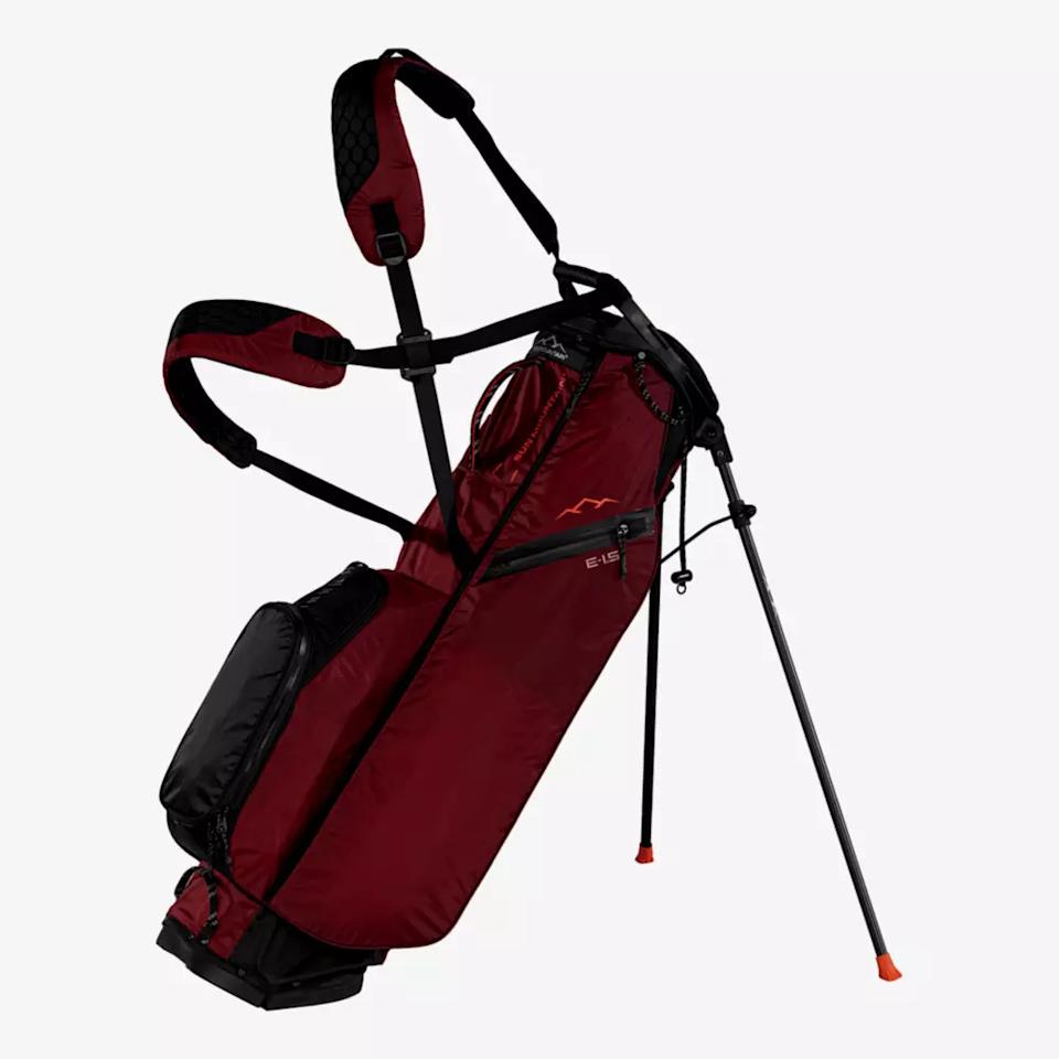 A maroon and black golf stand bag—one of the best golf bags 2026—features dual shoulder straps, several zippered pockets, and two extended legs, displayed upright on a white background.