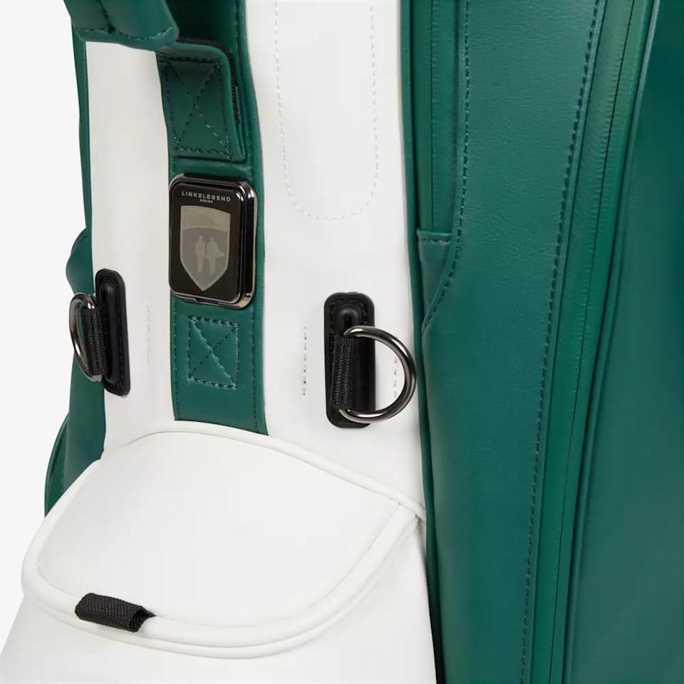 Close-up of a green and white golf bag, featuring metal rings and a black-and-silver Linksmaster logo badge above a pocket with a black pull tab—an example of the best golf bags 2026 has to offer.