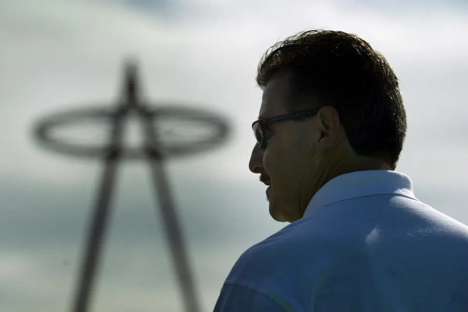 Angels owner Arte Moreno signs autographs and poses with fans with the Angel Stadium halo in the background.