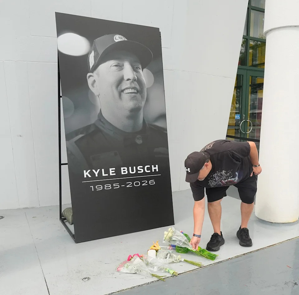 George Tobar from DeLand, Fl puts down flowers in front of makeshift memorial was made in front of the Daytona International Speedway tours building for NASCAR driver Kyle Busch, May 22, 2026, who died suddenly May 21, 2026.