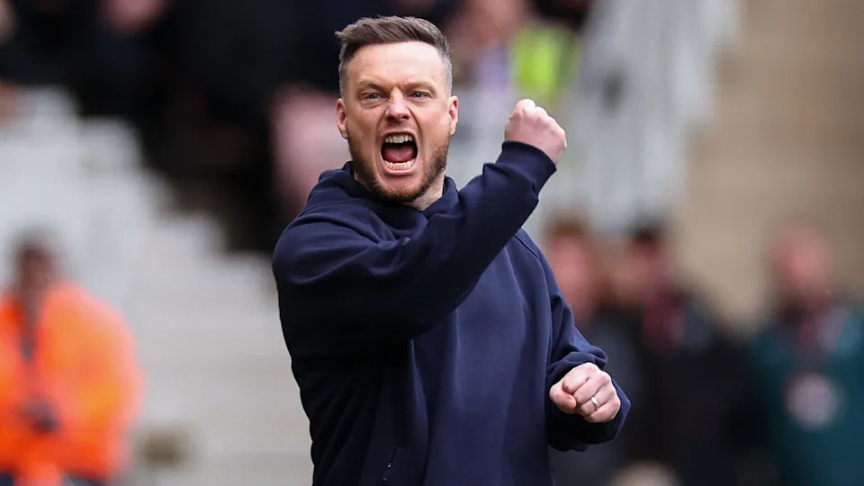 Kim Hellberg, wearing a navy blue sweatshirt, has his mouth open shouting while punching his right hand in the air and clenching his left fist to celebrate a Middlesbrough goal