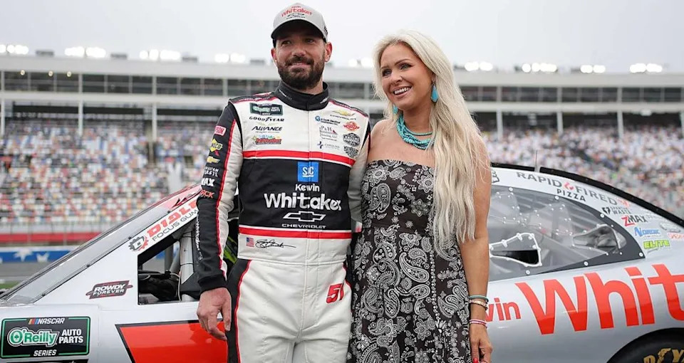 Jeremy Clements and his wife, Cortney, smile for photos on pit road at Charlotte Motor Speedway