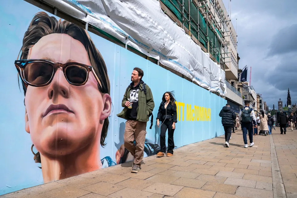 Members of the public pass by a mural featuring Scotland midfielder Scott McTominay on Princes Street in Edinburgh (PA)