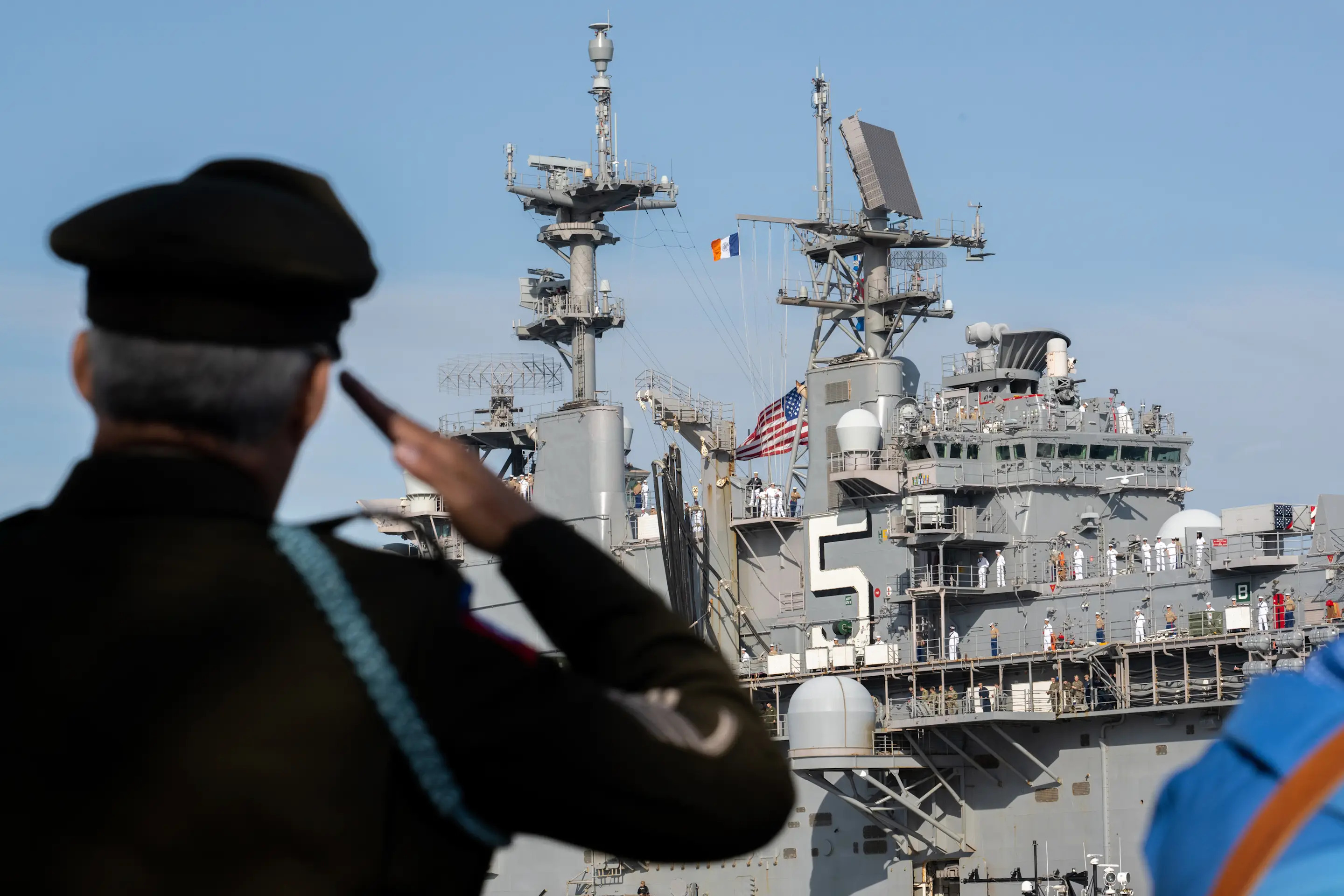 NEW YORK, NEW YORK - MAY 25: US Army Staff Sgt. Banjamin Marrero salutes as Marines and Navy sailors from the USS Bataan stand on the flight deck during their arrival for Fleet Week 2022 as seen from the Intrepid Museum on May 25, 2022 in New York City. Fleet Week returned this year in full capacity with over 3,000 sailors partaking across multiple vessels entering New York City's ports, according to reports. This is the first year since the start of the COVID-19 pandemic that Fleet Week has returned. (Photo by Alexi J. Rosenfeld/Getty Images)