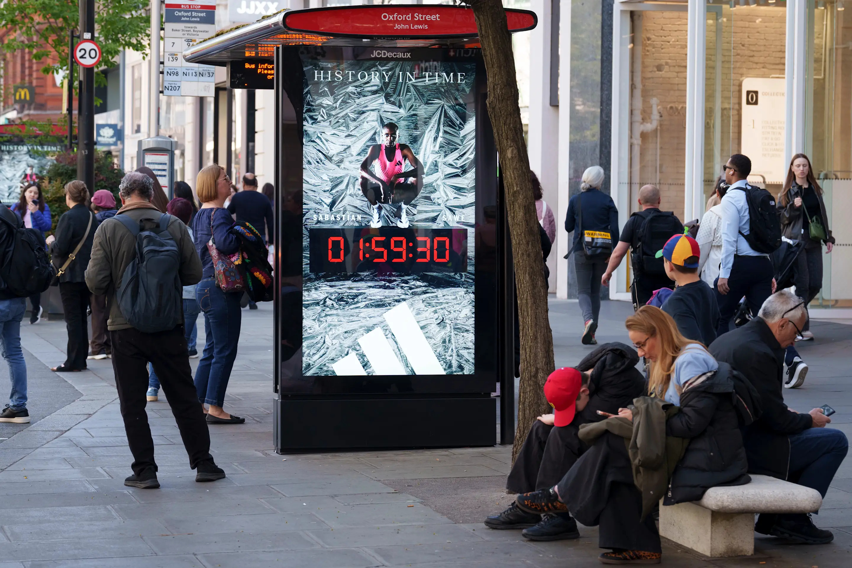 The morning after Kenyan runner Sabastian Sawe won the London Marathon with a world record time of 1:59.30, the first-ever sub-two-hour marathon in a competitive race, an ad for his historic achievement is displayed  in London's Oxford Street, on 27th April 2026, in London, England. Sawe was the first to beat the iconic 2hr barrier but in second place, and also under two hours, came the Ethiopian Yomif Kejelcha in his forst ever marathon. Both wore the Adidas Adizero Adios Pro Evo 3 which weighs a little over 97 grams. (Photo by Richard Baker / In Pictures via Getty Images)