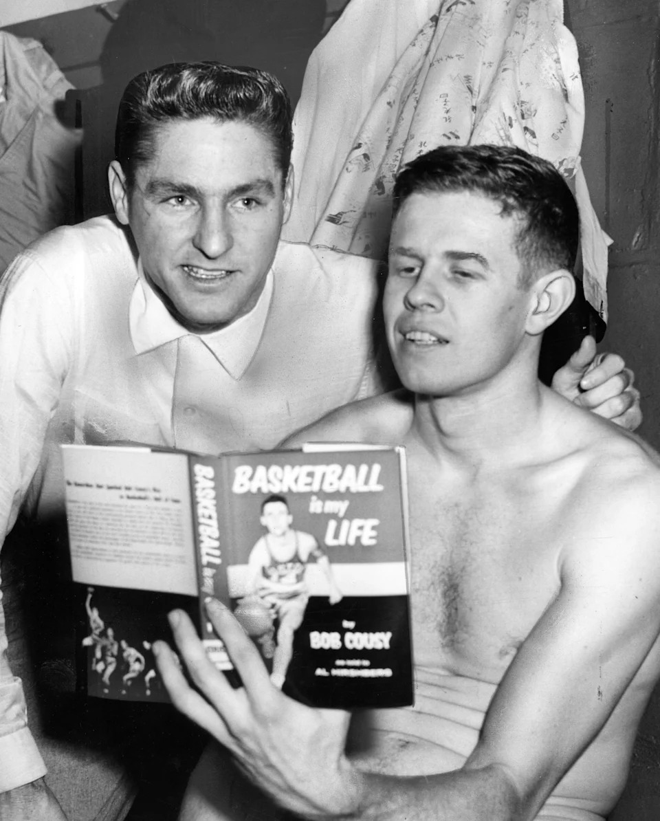 BOSTON, MA – APRIL 8: Boston Celtics players Bill Sharman, left, and Frank Ramsey read a copy of teammate Bob Cousy's book "Basketball is My Life" following a practice during the 1958 NBA World Championship Series in Boston on April 8, 1958. (Photo by Gil Friedberg/The Boston Globe via Getty Images) | Boston Globe via Getty Images