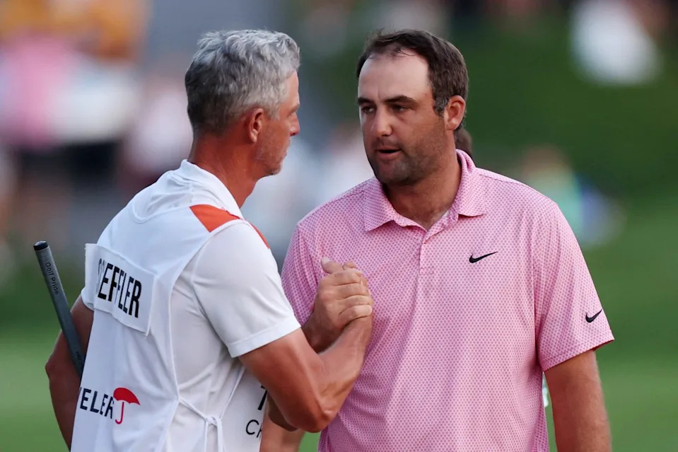Caddie Ted Scott and Scottie Scheffler of the United States shake hands on the 18th green after finishing their round during the final round of the Travelers Championship 2026. Getty Images