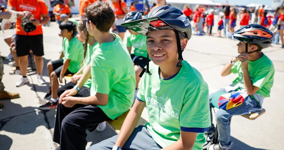 Kid wearing bike helmet give out at The NASCAR Foundation