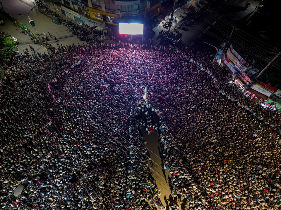 A high-altitude drone shot depicts a large crowd of people around a central city monument to view the live broadcast of the Argentina vs. Spain World Cup final in Chattogram, Bangladesh, on July 20, 2026. Chattogram's World Cup events peaked at midnight as football fans gathered at giant-screen venues, captured in bird's-eye views at CRB Shirishtala, Kazir Dewri, and No. 2 Gate. Despite Argentina's defeat to Spain, locals attended the grand finale. (Photo by Zakir Hossain/NurPhoto via Getty Images)